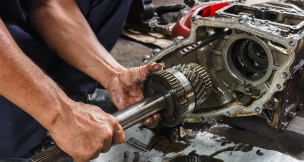 A technician's hands working on a transmission rebuild.